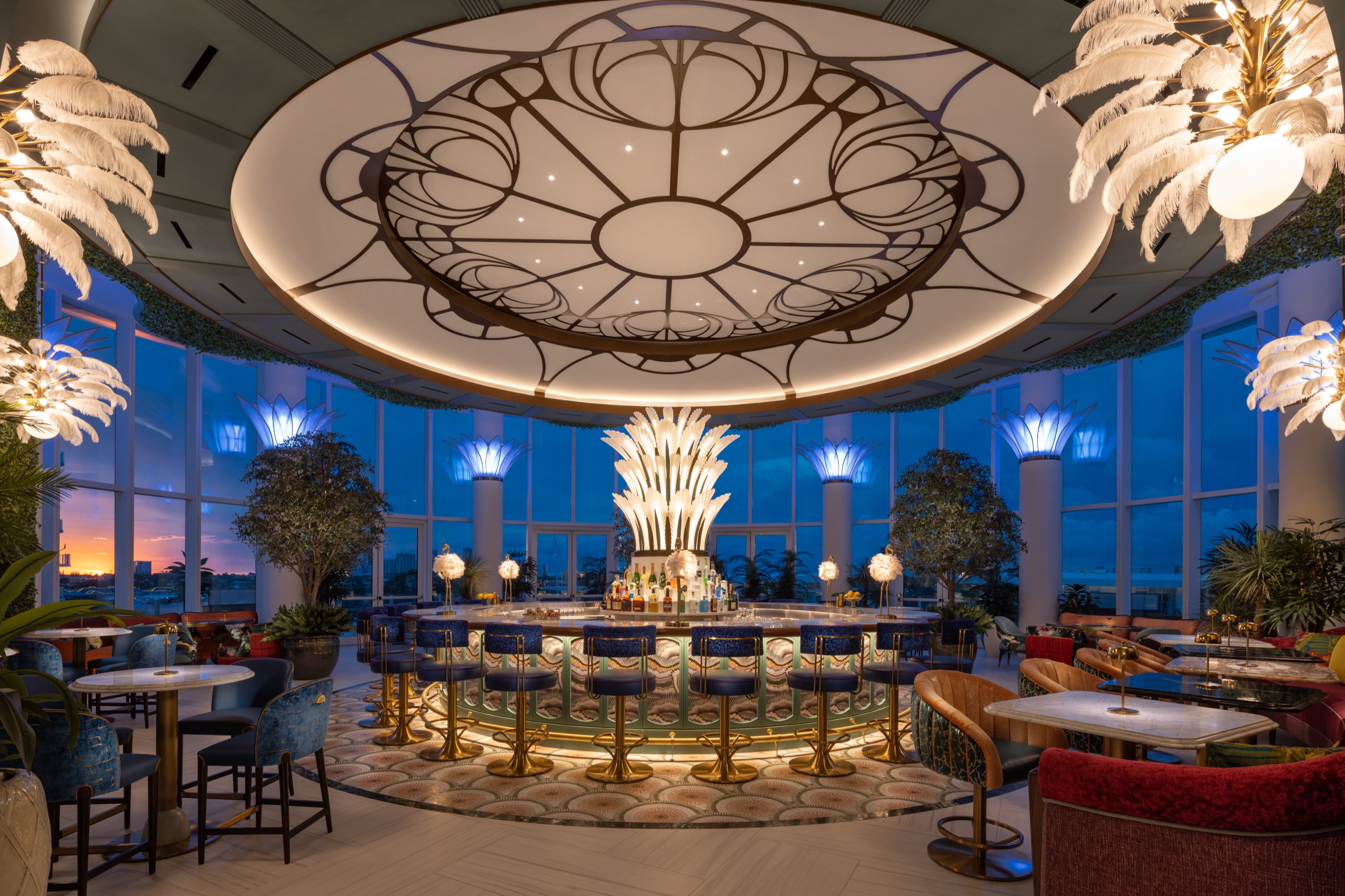 The circular bar photographed at dusk — glass plumes lit, sunset behind the columns