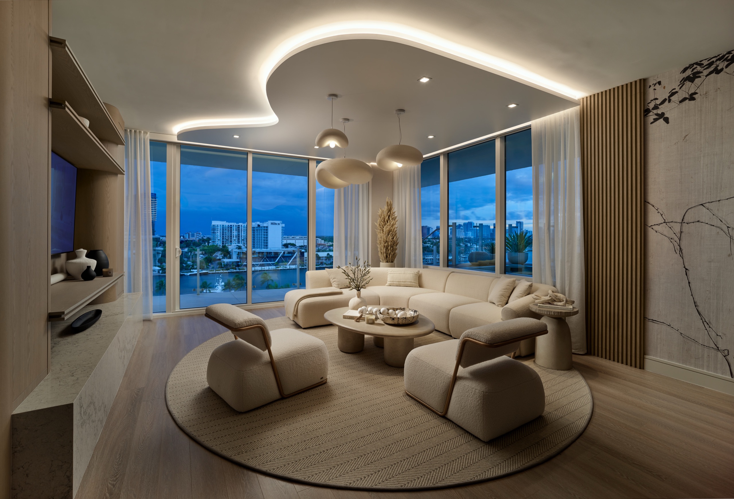 The living room at dusk under a sculpted light cove, the waterway below